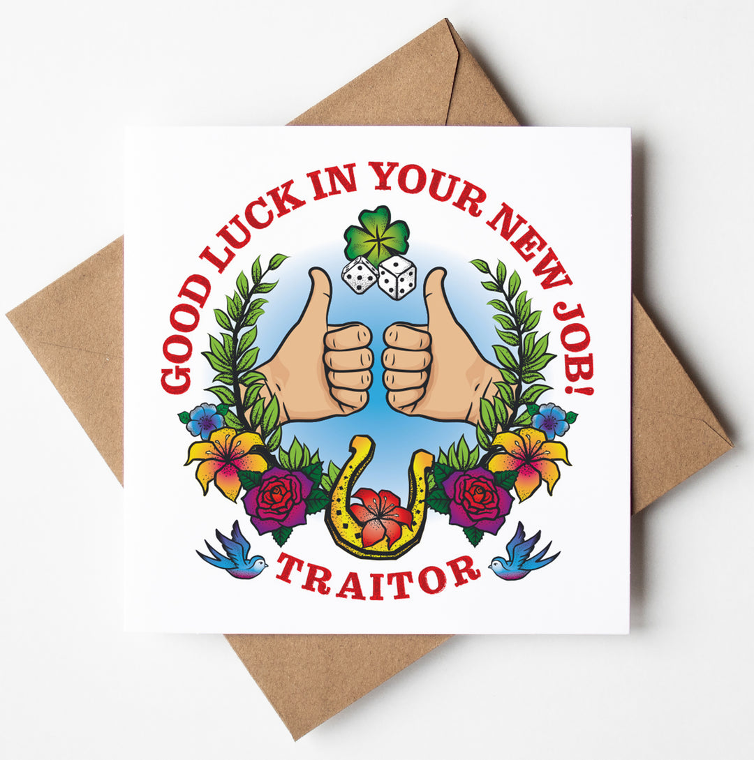 The Good Luck New Job Tattoo Card showcases a tattoo-inspired design featuring two thumbs up, surrounded by flowers, a horseshoe, and dice. The text reads "Good Luck In Your New Job!" alongside "Traitor" in bold red letters. The card is paired with a brown envelope.