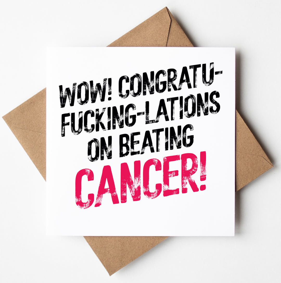 The "Congratulations On Beating Cancer! Sweary Card" features bold text that exclaims, "WOW! CONGRATU-FUCKING-LATIONS ON BEATING CANCER!" with "CANCER" highlighted in pink. It sits atop a brown envelope, making for a striking presentation.