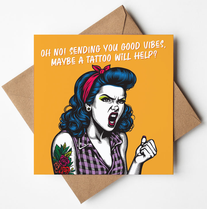 The "Oh No! Sending You Good Vibes, Maybe A Tattoo Will Help?" funny motivational friendship vintage babes card stars a blue-haired cartoon woman shaking her fist with the quirky message: “Oh no! Sending you good vibes, maybe a tattoo will help?”.