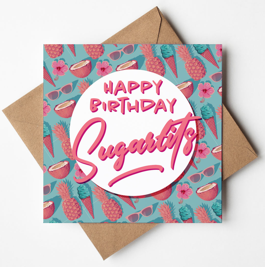 The "Happy Birthday Sugartits" card features the text in pink on a white circle, with tropical elements such as pineapples, sunglasses, coconuts, and ice cream decorating the teal background. It comes with a brown envelope and biodegradable packaging for an eco-friendly gift option.