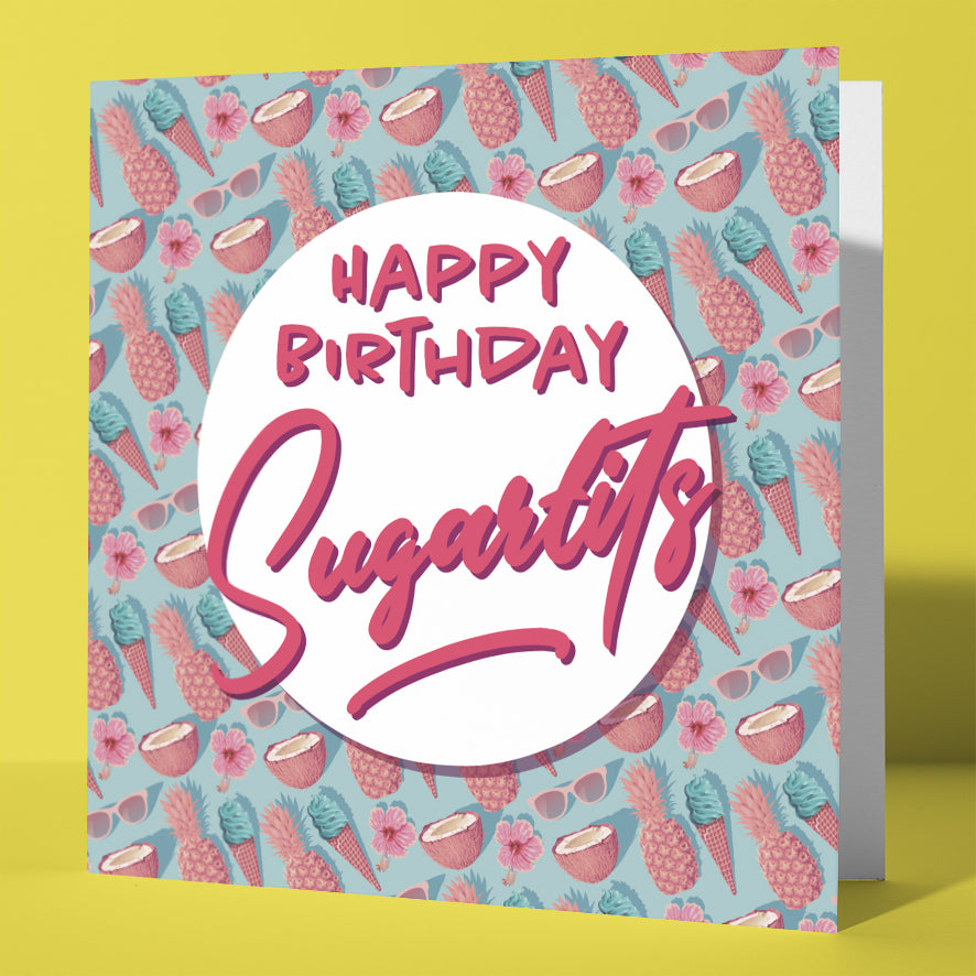 The Happy Birthday Sugartits Tropical Card features bold pink text on a white circle, surrounded by pineapples, coconuts, flowers, and sunglasses—a funny and colorful UK birthday card for any celebration.