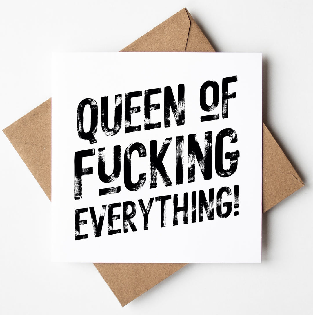 The Queen of Fucking Everything! Harlem Card, a square birthday card featuring bold black text that reads "QUEEN OF F*CKING EVERYTHING!" on a white background and designed in Wales, is neatly placed on top of a brown envelope.