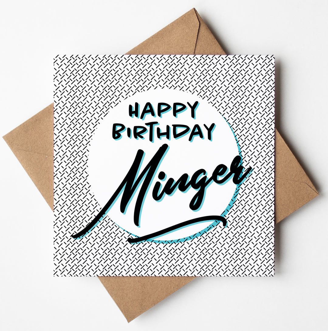 A square "Happy Birthday Minger Card" featuring bold text and a black and white crosshatch background is included with a plain brown envelope, prepared for global shipping.