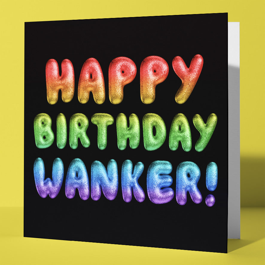 The Happy Birthday Wanker! Rainbow Font Card is a UK-designed greeting card with "Happy Birthday Wanker!" in shiny, balloon-like rainbow letters against a black background and set on a yellow card.