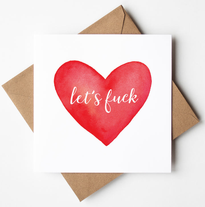 The "Let's Fuck Card" showcases a striking red heart with the phrase "let's fuck" in elegant white script on the front. Ideal for delivering bold messages, it comes with a brown envelope and is set against a pristine white background.