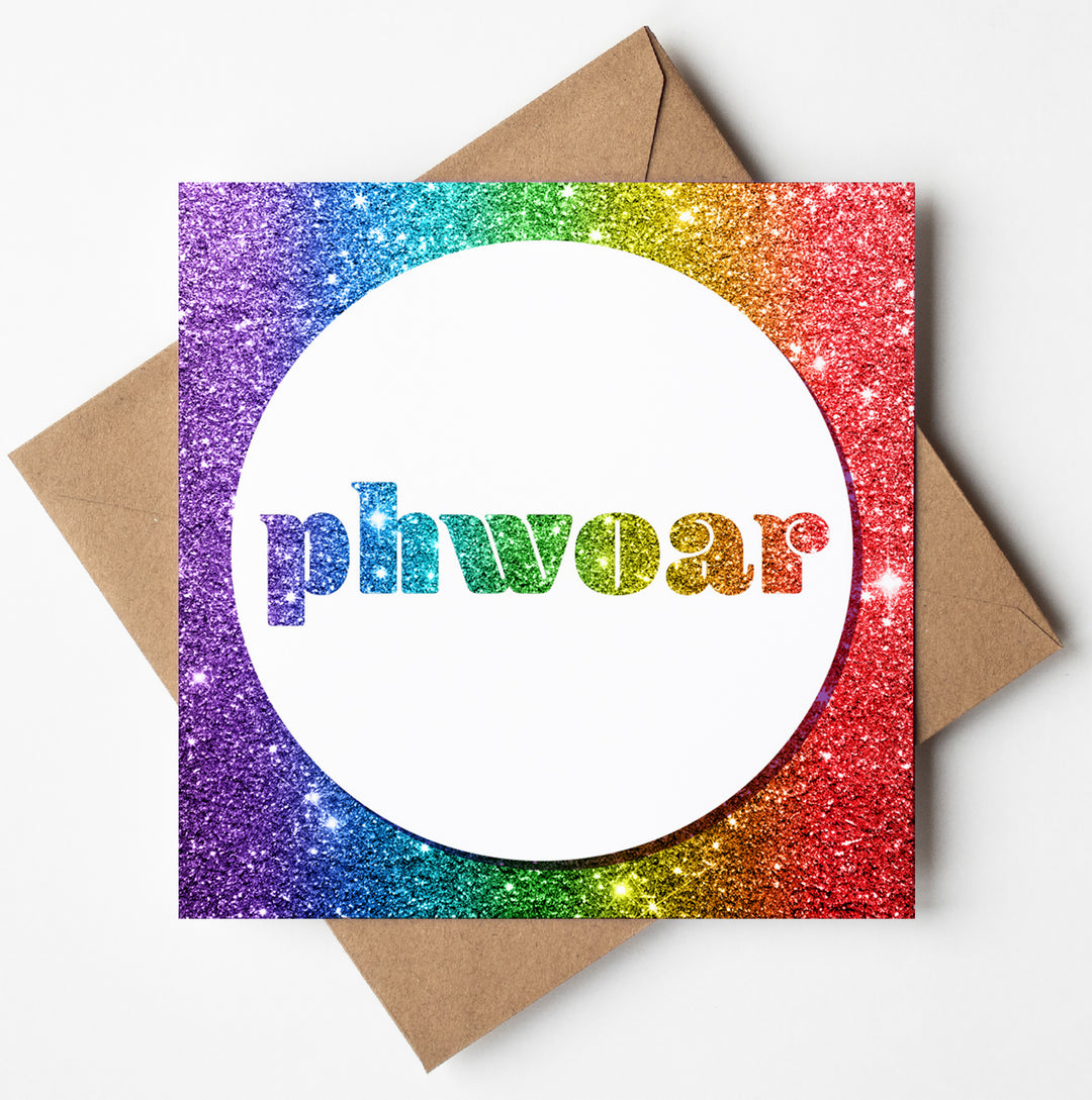 The Phwoar Glitter Card features a sparkling rainbow glitter design, making it perfect for any special occasion. The word "phwoar" is displayed in dazzling rainbow glitter letters against a white circular background. This card, ideal for Valentine's Day or an anniversary, comes with a charming brown envelope.