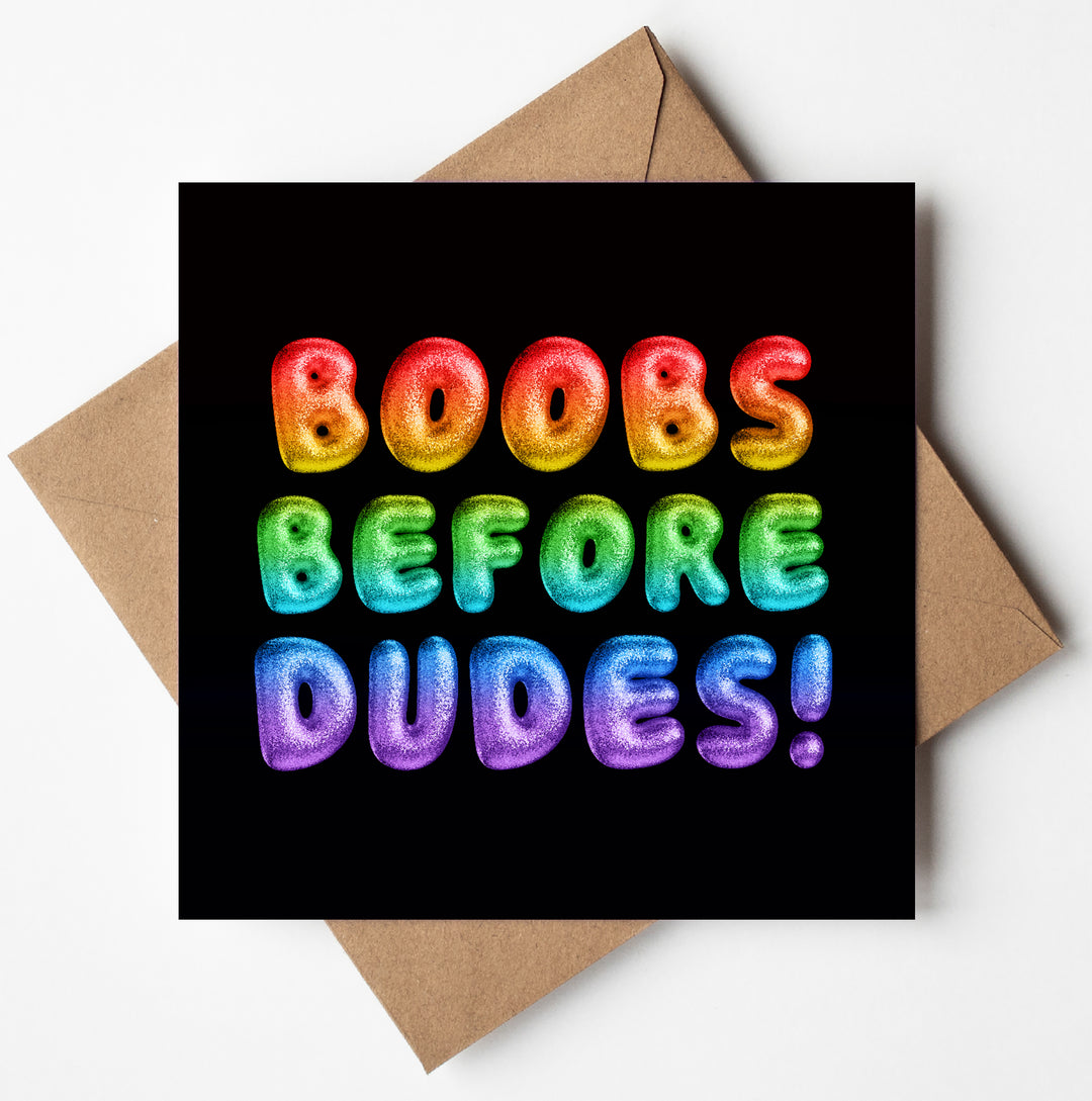 A Rainbow Font Card featuring vibrant, bold text declares "BOOBS BEFORE DUDES!" on a black background. This Boobs Before Dudes Card makes for a cheeky greetings card.