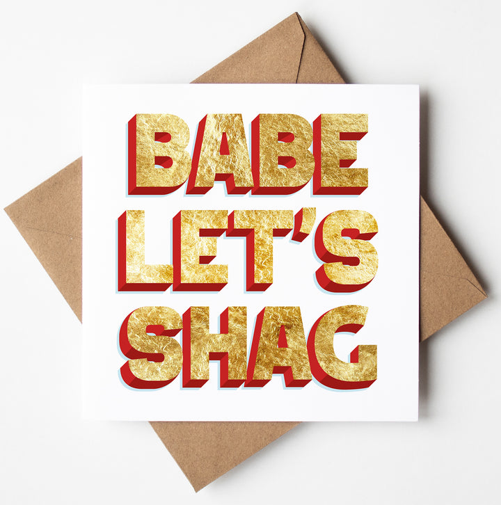 A greeting card with bold, gold and red block letters reads "BABE LET'S SHAG" on a white background, perfect as a funny Valentine card, and comes with a brown envelope.