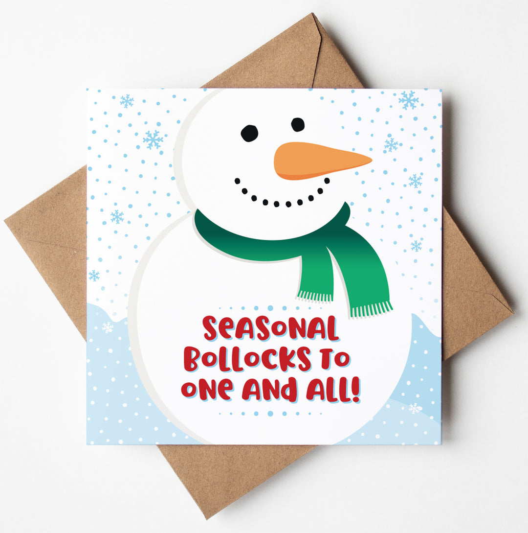 A funny Christmas card featuring a smiling snowman with a green scarf and the text "Seasonal Bollocks to One and All!" on a snowy background, placed on a brown envelope. Perfect for those who enjoy a touch of naughty Xmas humour.