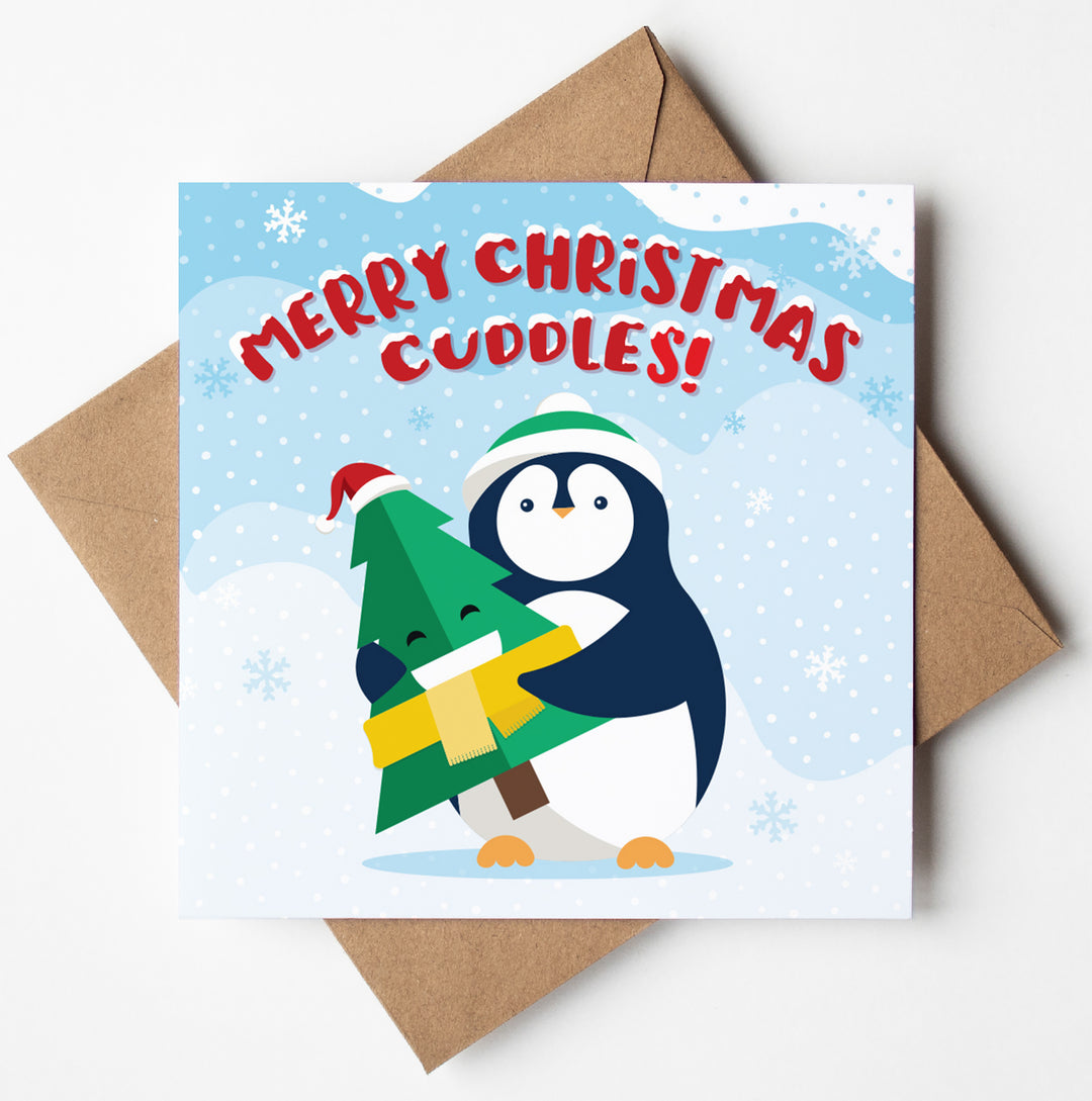 An illustrated Christmas card with a penguin hugging a Christmas tree against a snowy background. The card reads, "Merry Christmas Cuddles!" and rests on a brown envelope, adding a touch of funny Christmas charm to your holiday greetings.