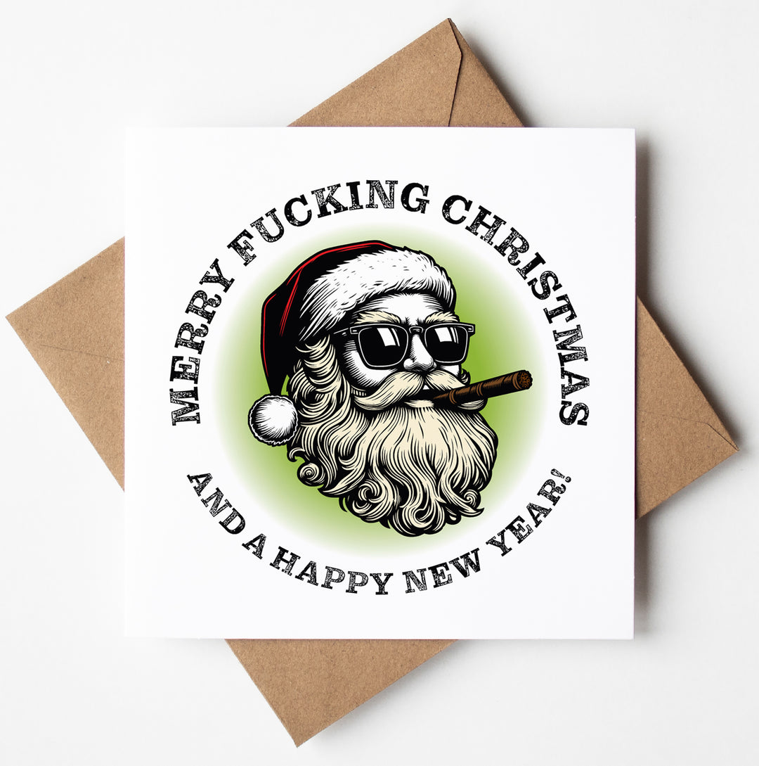 The Sunglass Santa's Merry Fucking Christmas and a HNY Xmas Card showcases a playful Santa sporting sunglasses and puffing on a cigar. The card features the cheeky message, "Merry Fucking Christmas and a Happy New Year!" It is accompanied by a brown envelope.