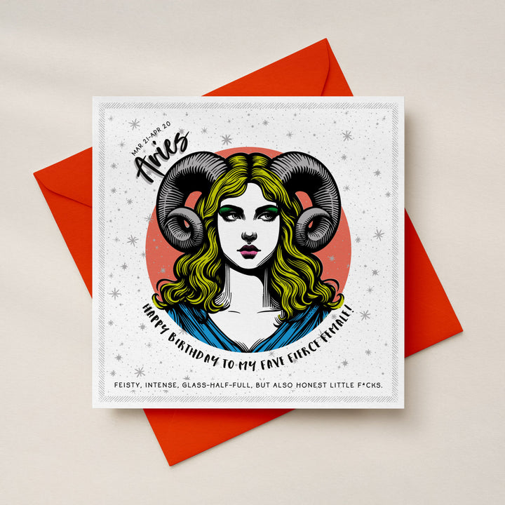 A square birthday card with a white background and silver foil detailing and a central illustrated ram-horned woman with green hair, placed on top of a Neo Flare orange envelope. The card reads 'Aries' and 'Happy Birthday to My Fave Fierce Female' with smaller text below.