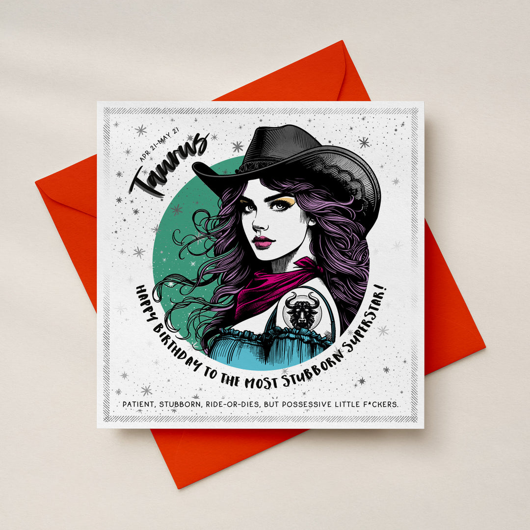 A square birthday card with a western-themed birthday card featuring a woman with a black cowboy hat, long wavy purple hair, a pink scarf, and a blue dress on a white silver foil starry background. Text reads 'Taurus', 'Happy Birthday to the Most Stubborn Superstar!'
placed on top of a bright orange envelope against a light background. 