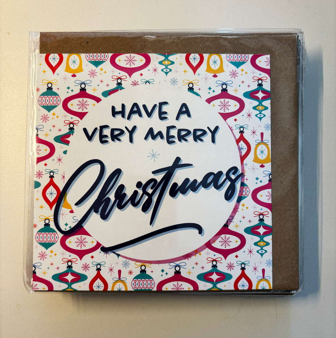 The SALE! Have a Very Merry Christmas Bright Baubles Navy Card is a square card with colorful ornaments, festive lettering, and snowflakes. Packaged in a biodegradable bag with worldwide shipping available.