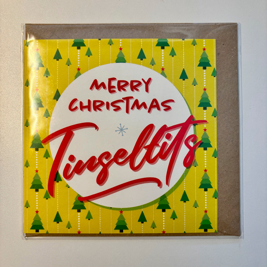 The SALE! Merry Christmas Tinseltits Trees Citrus Yellow Card is a UK-printed, biodegradable square card featuring red text on a white circle with green trees and red stars on yellow, presented in a brown envelope for festive fun.