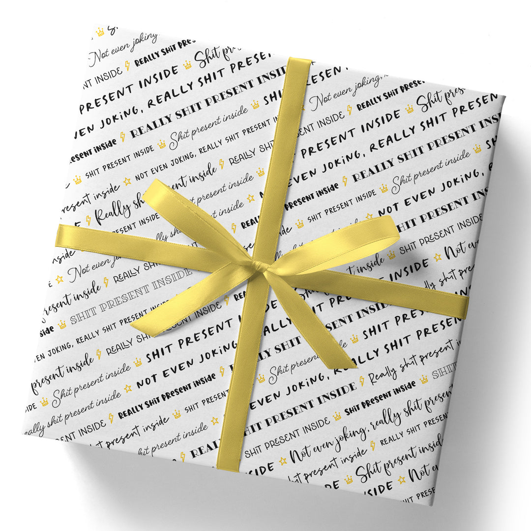 A square gift wrapped in Shit Present Gift Wrap (Folded Sheet), a silky wrap with playful black and gold text: “Not even joking, really shit present inside,” completed with a shiny yellow ribbon and bow.