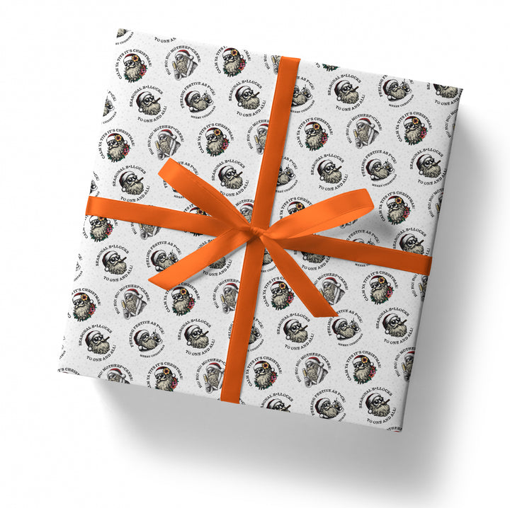 Gift box wrapped in paper with a sunglass wearing santa pattern and an orange ribbon on a white background