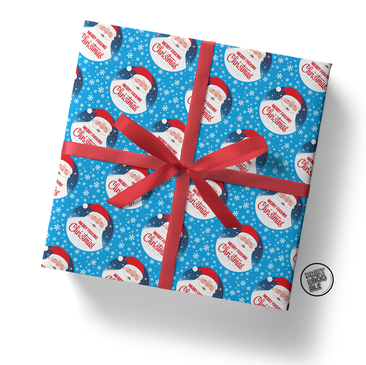 A square gift box wrapped in Merry Fucking Xmas Santa Gift Wrap, featuring designs of Santa Claus, snowflakes, and "Merry Christmas" text. It's adorned with a bright red ribbon and bow, with a small round logo visible in the bottom right corner.