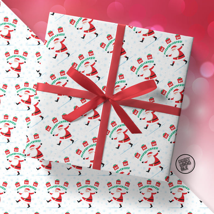 A gift wrapped in SALE! Ho Ho Ho Motherfuckers! (Folded Sheet) funny xmas paper, topped with a red ribbon bow, with more of the same festive wrapping featuring bold holiday cheer text in the background.
