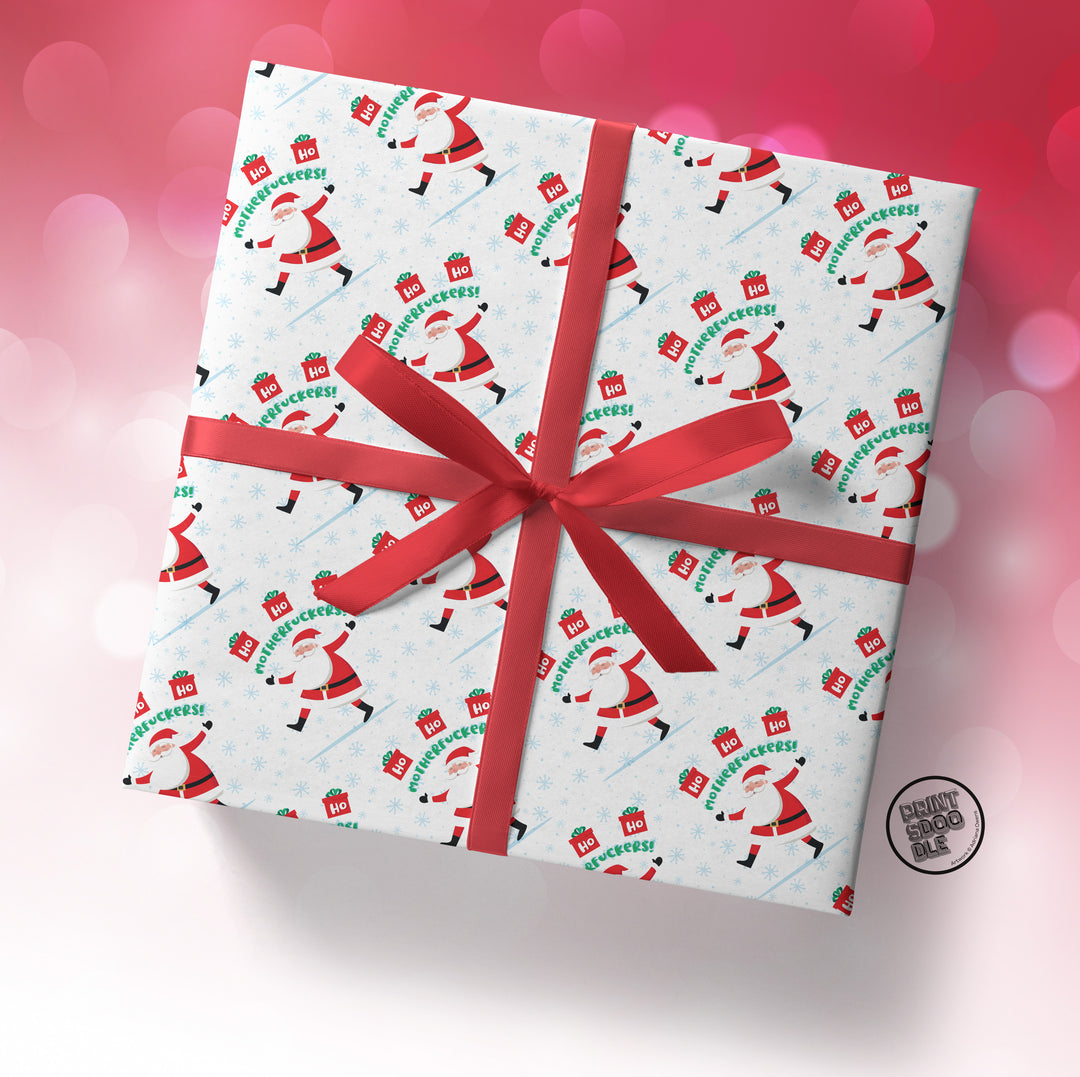 A gift box wrapped in the "SALE! Ho Ho Ho Motherfuckers!" folded sheet, tied with a red ribbon and bow, set against a pink and red bokeh background.
