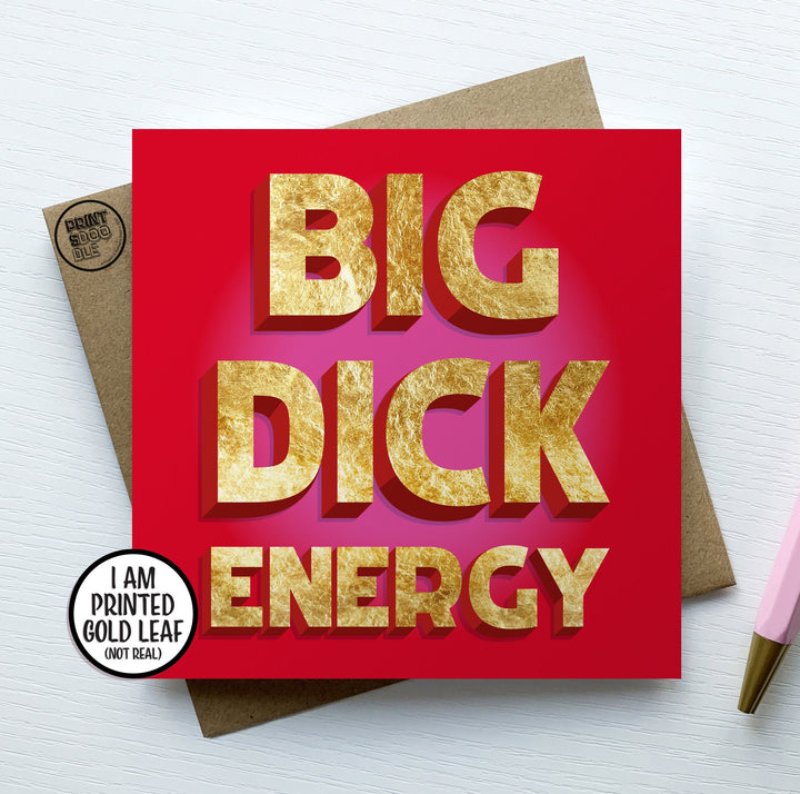 The Big Dick Energy Card features bold, gold text on a red background proudly declaring "BIG DICK ENERGY." A small circle notes it is "PRINTED GOLD LEAF (NOT REAL)." Ideal for cheeky occasions, it includes an envelope and pen against a white surface to complete the package.