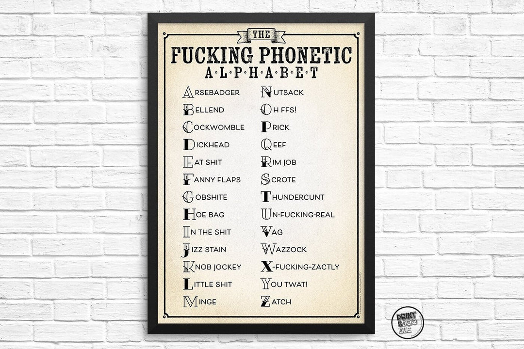 The "Rather Rude and Funny Fucking Phonetic Alphabet Print" lists A-Z with profanities and insults in a vintage cream design against a white brick wall—perfect as humorous, obscene home office wall art.